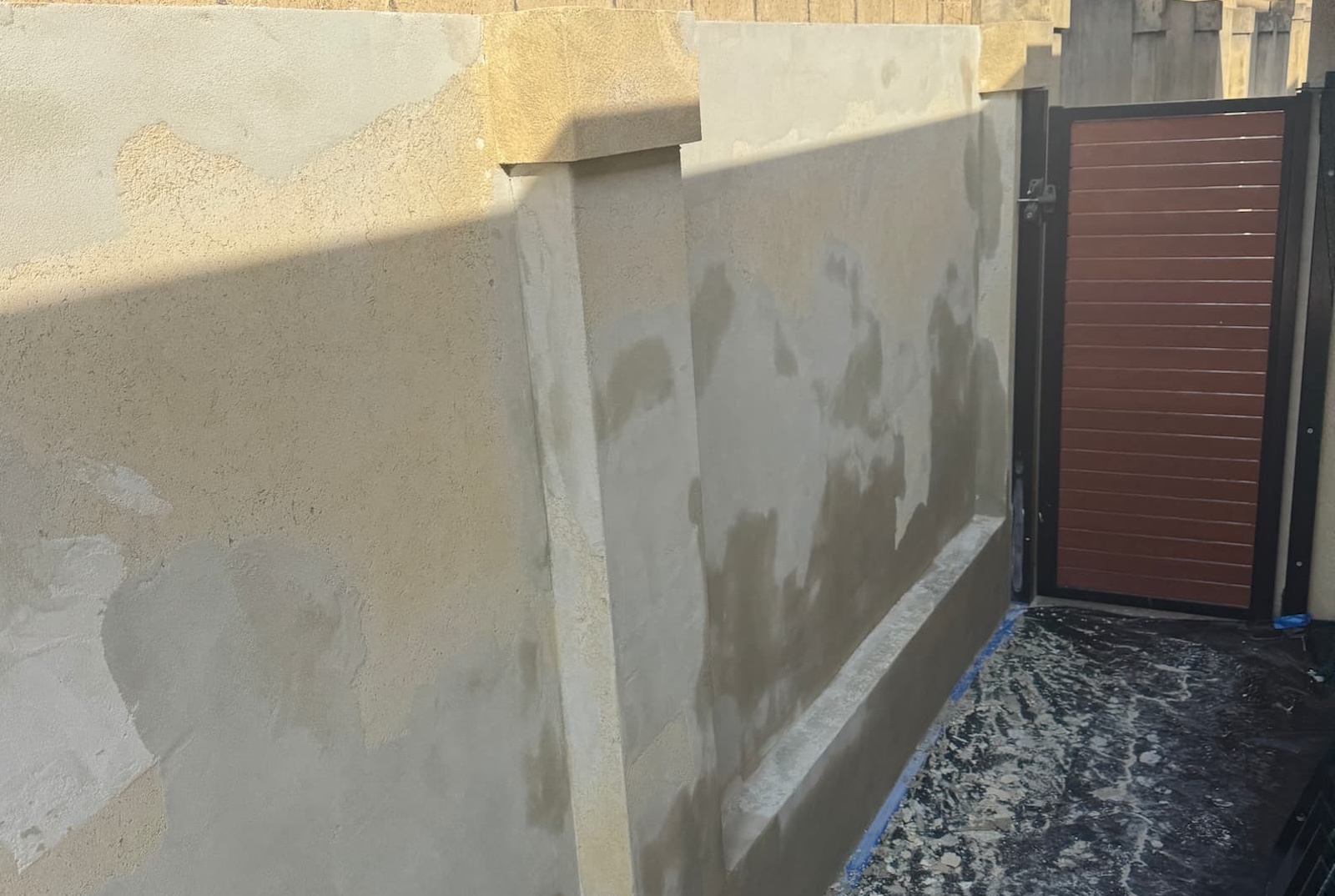 Sorrento boundary wall before works, showing mismatched render patches